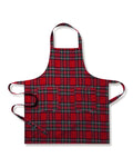 Two Petite Plume Adult Aprons in Imperial Tartan hang on a wooden rack with a patterned white dish towel. Perfect for holiday baking, a wooden spoon and spatula peek from an apron pocket against a warm, beige wall backdrop, creating an inviting scene for cozy cooking adventures.