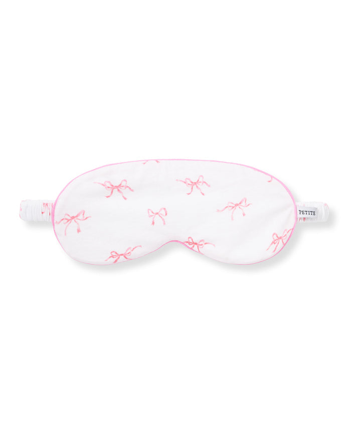 The Adult Pima Sleep Mask in Blushing Bows features a white design with pink bows, pink trim, an elastic strap, and a side tag that reads "PETITE.