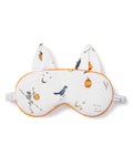The Petite Plume Adults Twill Kitty Sleep Mask in Trick or Treat features a white design with orange trim, festive icons like a skeleton, bird, bats, pumpkins, stars, and trick or treat text. With cat ears and an adjustable strap, it adds spooky style to your sleep routine!.
