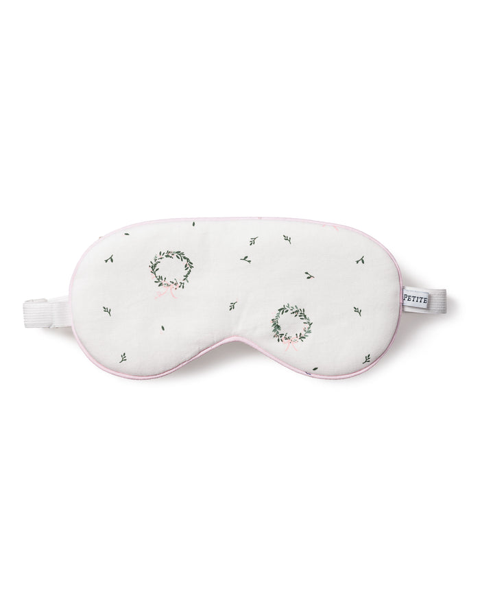 The Petite Plume Adults Twill Sleep Mask in Somerset Wreath features white twill, embroidered green and pink wreaths, black stitching, a white elastic strap, soft pink trim, and a PETITE tag—perfect for matching or gifting.