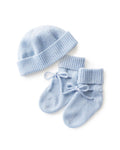 The Baby Cashmere Bootie & Hat Set in Light Blue features a knitted baby hat and matching booties with ribbed cuffs and tied bows, displayed on a white background.