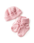 The Baby Cashmere Bootie & Hat Set in Rose features a pink knitted baby hat and matching booties with folded cuffs and tied laces, displayed on a white background.