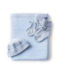 The Baby Cashmere Bundle in Light Blue features a neatly folded knit blanket, a matching baby hat, and knit booties with ribbons, all beautifully arranged on a white background.