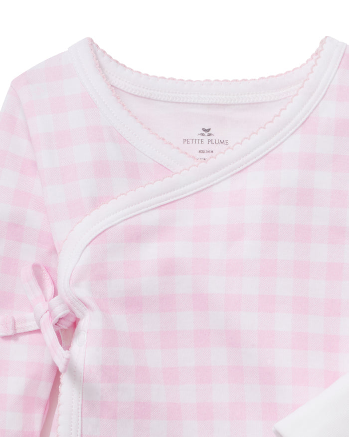 Baby Pima Wrap Set in Pink Gingham features a pink and white gingham pattern with a wrap-style front, white trim, and a small bow on the left side. The PETITE PLUME brand label is visible at the neckline.