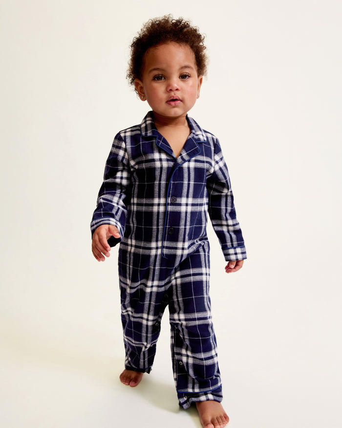 The Baby's Brushed Twill Classic Romper in Oxford Tartan is a full-length, long-sleeve children's onesie featuring a navy, white, and gray plaid pattern with a button-up front, collar, and snap leg closures.
