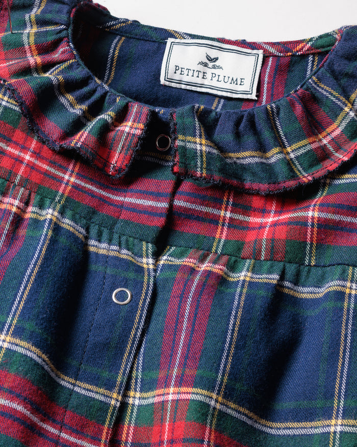 Close-up of the Babys Brushed Cotton Madeline Romper in Windsor Tartan by Petite Plume, featuring a plaid design with red, green, and blue colors, a ruffled collar, and snap buttons. The label ensures it is chemical-free for comfort and peace of mind.