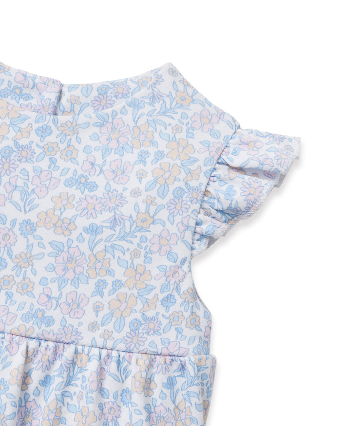 The Baby's Pima Isla Play Romper in Fleur Blanche features light blue and white florals, short ruffled sleeves, and elastic leg openings, shown laid flat on a white background.