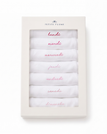 A boxed set from Petite Plume contains seven white Baby’s Pima Long Sleeve Onesies in French Lessons Pink, each embroidered with a day of the week in French and arranged in order from lundi (Monday) to dimanche (Sunday). The Petite Plume brand name appears on the box.