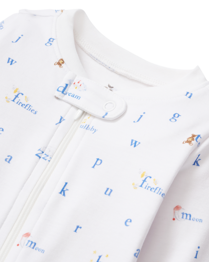 Close-up of the Baby’s Pima Romper in Letters and Lullabies—a white zippered onesie featuring blue letters, words like “dream,” “fireflies,” and “moon,” and small animal illustrations.
