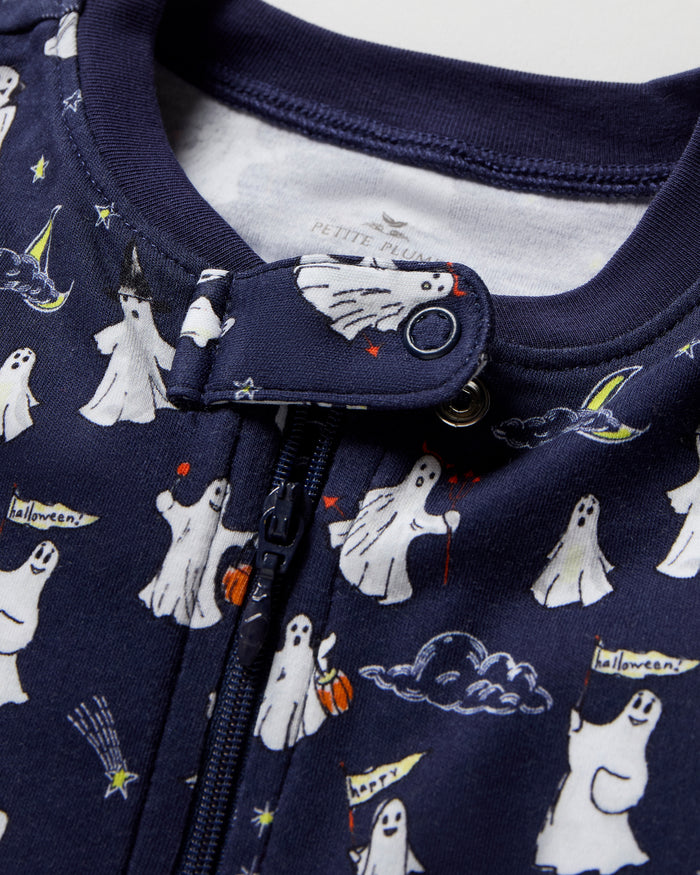 The Baby's Pima Romper in Spooky Slumber is a navy blue, long-sleeve, footed sleeper with a front zipper and features white polar bears in scarves and hats, stars, and geometric shapes on soft fabric.