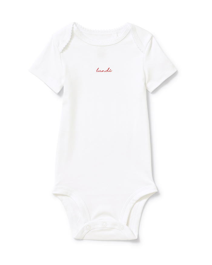A pink short-sleeve baby onesie from the “Baby’s Pima Short Sleeve Onesie Set in French Lessons Pink,” featuring “lundi” embroidered in small red letters on the chest and snap buttons at the bottom.