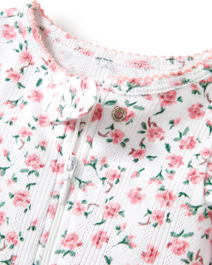 Baby's Pointelle Footie Romper in Pink Floral features a white long-sleeve footed onesie with a pink and green floral print, shown flat on a white background.