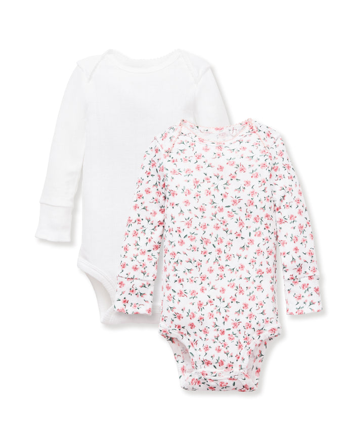The Baby's Pointelle Long Sleeve Onesie Set of 2 includes a plain white bodysuit and a white bodysuit with a pink floral print, both featuring envelope necklines and snap closures at the bottom.