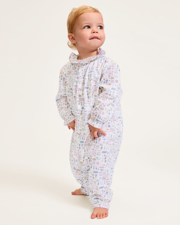 The Baby's Twill Madeline Romper in Baking Spirits Bright features long sleeves, a ruffled collar and cuffs, pastel kitchen print on white, front buttons, and snap closures at the legs for easy dressing.