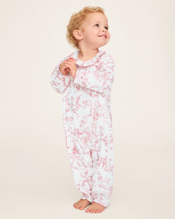 The Baby's Twill Madeline Romper in Pink Timeless Toile features long sleeves, pink toile floral and tree patterns, ruffled cuffs and collar, and convenient inseam snaps for easy diaper changes.