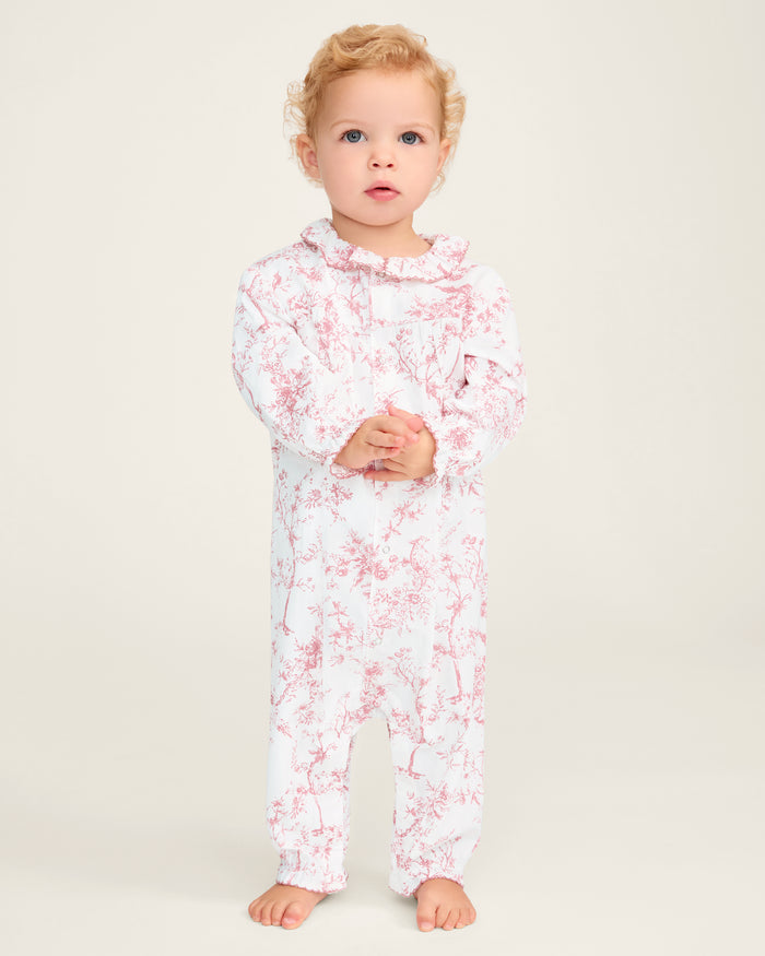 The Baby's Twill Madeline Romper in Pink Timeless Toile features long sleeves, pink toile floral and tree patterns, ruffled cuffs and collar, and convenient inseam snaps for easy diaper changes.
