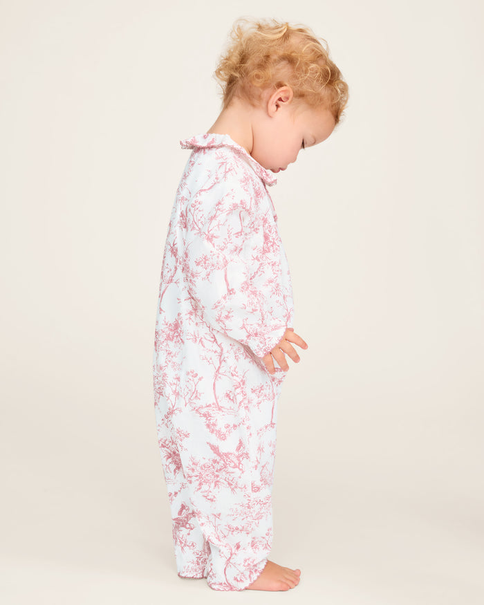 The Baby's Twill Madeline Romper in Pink Timeless Toile features long sleeves, pink toile floral and tree patterns, ruffled cuffs and collar, and convenient inseam snaps for easy diaper changes.
