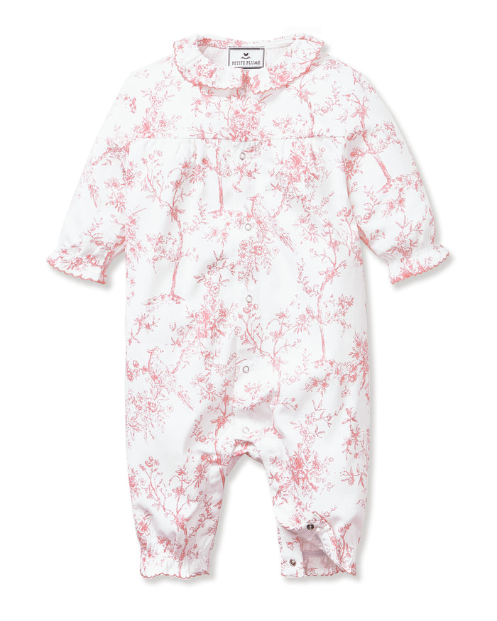 The Baby's Twill Madeline Romper in Pink Timeless Toile features long sleeves, pink toile floral and tree patterns, ruffled cuffs and collar, and convenient inseam snaps for easy diaper changes.