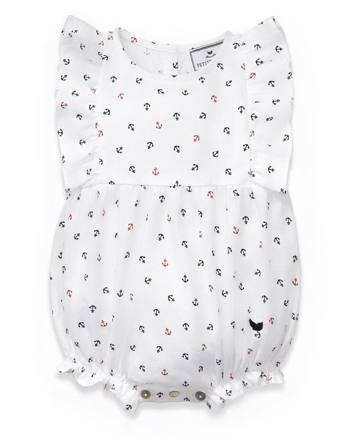 The Baby’s Twill Ruffled Romper in Anchors Away White features flutter sleeves and is adorned with charming navy blue and red anchor patterns. It includes elastic leg openings and snap buttons at the bottom for easy changing.