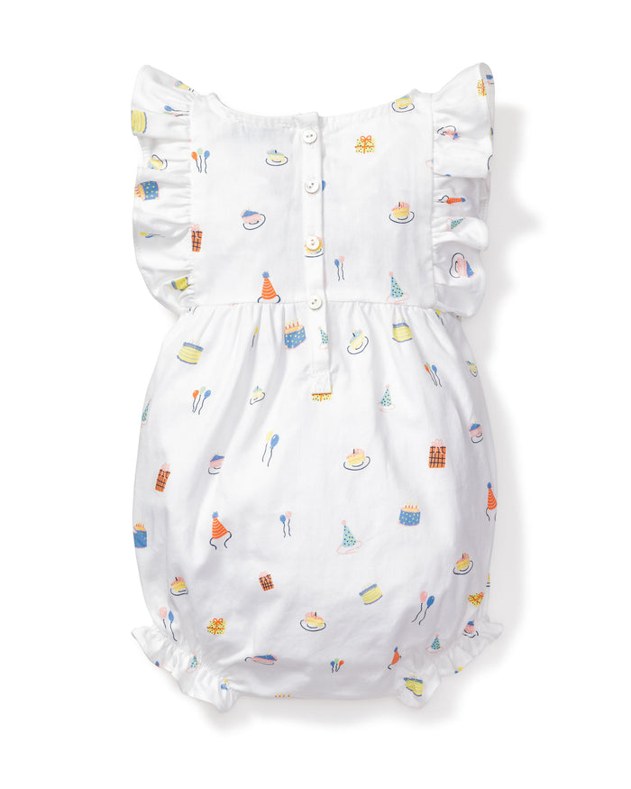 Petite Plumes Babys Twill Ruffled Romper in Birthday Wishes is a white romper with ruffled sleeves featuring colorful cake, candle, and party hat designs inspired by the Victorian era. It includes front buttons for easy fastening.