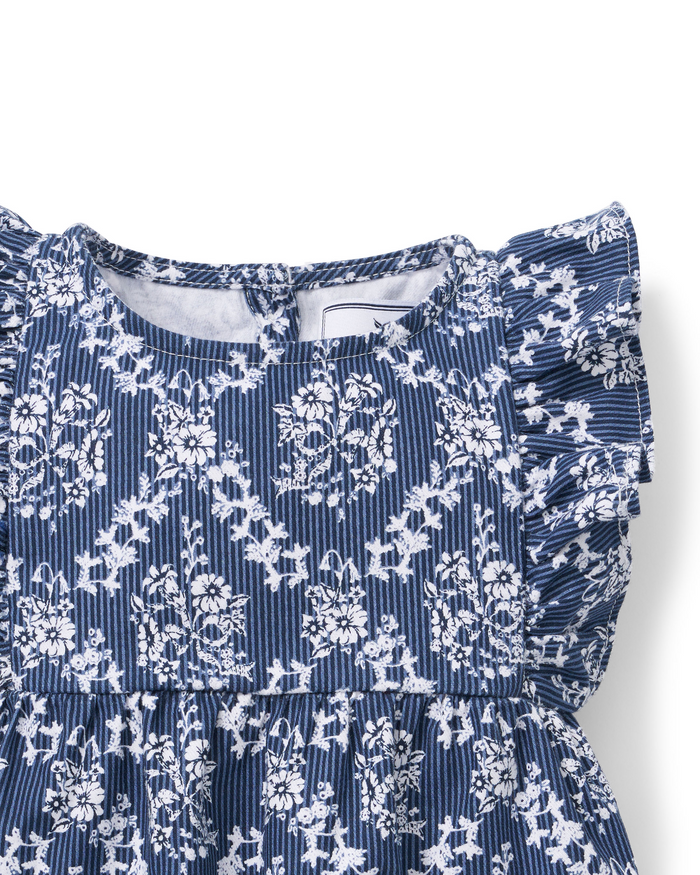 Baby’s Twill Ruffled Romper in Innkeeper Trellis, featuring a blue and white floral pattern with ruffled sleeves and a round neckline, shown close up against a white background.