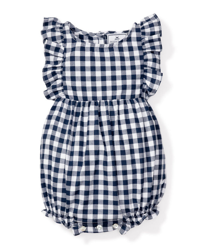 The Petite Plume Babys Twill Ruffled Romper in Navy Gingham is made from yarn-dyed cotton featuring a navy and white checkered pattern, ruffled sleeves, elastic bottoms with button closures, and lightweight fabric ideal for warm weather sleepwear.