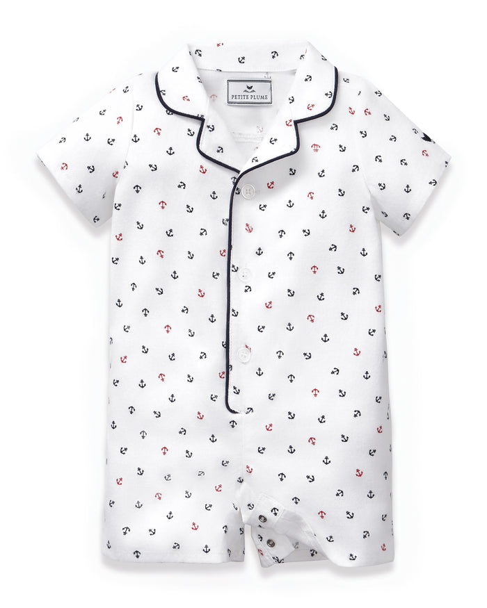 Baby’s Twill Summer Romper in Anchors Away White features short sleeves, a white base with navy and red anchor print, navy piping on the collar and trim, and convenient side snap buttons.