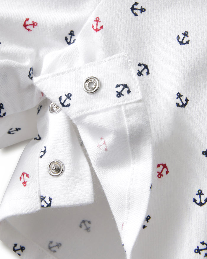 Close-up of the Baby’s Twill Summer Romper in Anchors Away White, showcasing soft white fabric with small navy and red anchor prints and metal snap buttons.