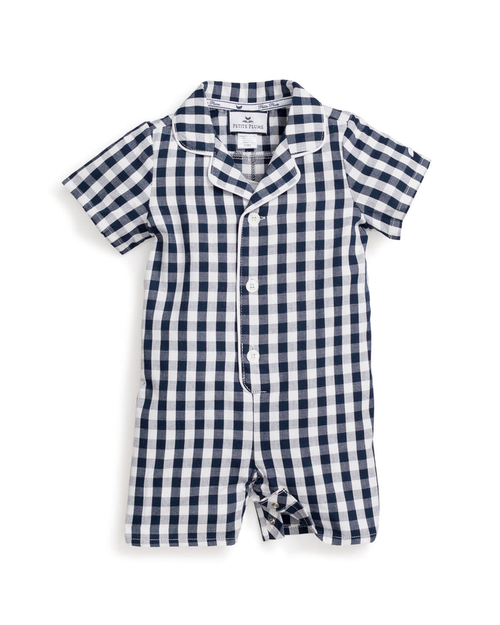The Petit Plume Babys Twill Summer Romper in Navy Gingham is a short-sleeved, one-piece outfit with a navy and white checkered pattern, button-down front, white piping, and a small collar for an elegant look.