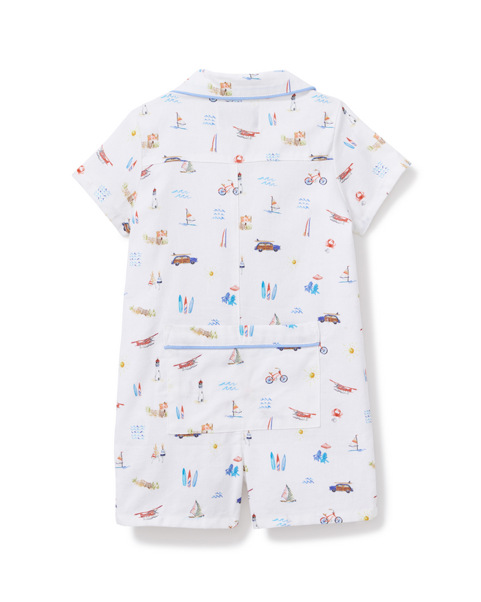 Baby’s Twill Summer Romper in Summer Nostalgia features short sleeves and a white base adorned with whimsical beach-themed illustrations—cars, bicycles, surfboards, and sailboats. Shown from the back, it includes a large pocket and blue piping accents for added detail.