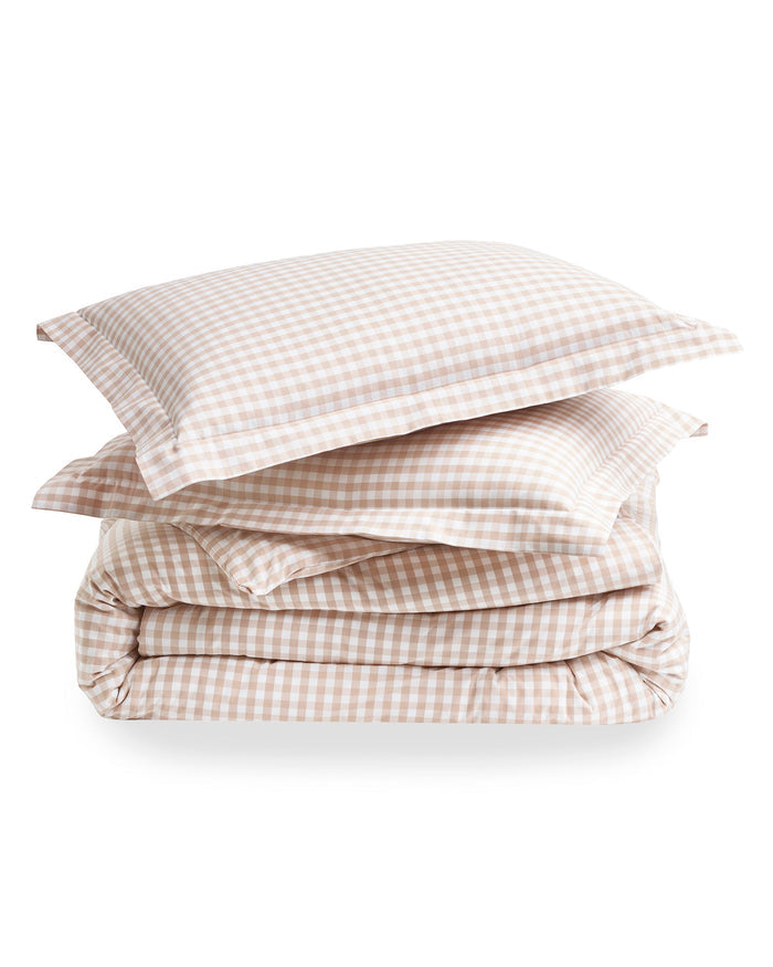 The Luxe Premium Percale Duvet Set in Camel Gingham features two pillows and a folded comforter with a beige and white gingham check pattern, neatly stacked on a white background.