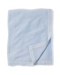 A neatly folded Cashmere Baby Blanket in Indigo by Petite Plume, with a luxuriously soft texture. The bottom right corner is slightly turned up, showcasing the underside. Edges are bordered with a darker indigo shade, evoking the elegance of a luxury baby gift.