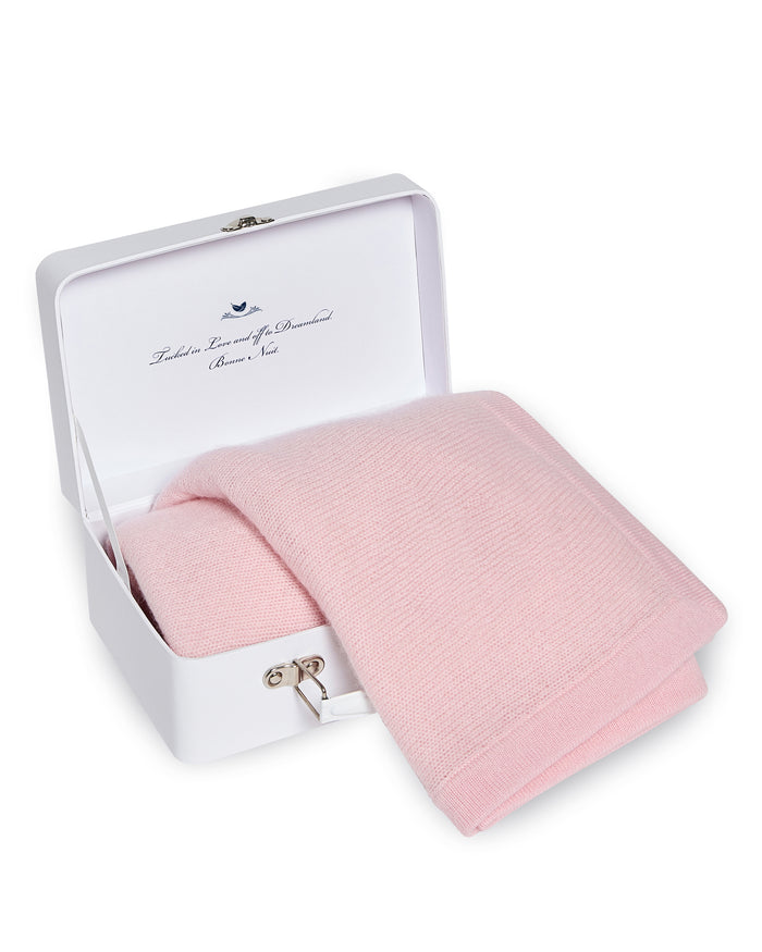 The Cashmere Baby Blanket in Rose by Petite Plume is handmade in Nepal, folded inside a white box with a silver latch. The luxury baby gifts interior lid showcases a printed message and an illustration of a small blue bird.