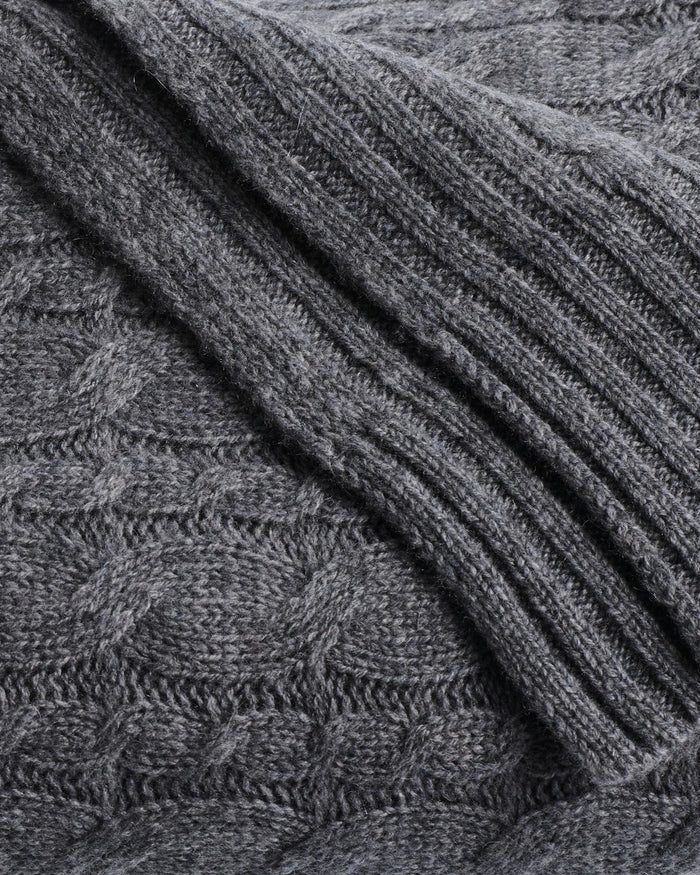 Close-up of Petite Plumes Cashmere Cable Knit Throw in Dark Grey featuring a ribbed texture on the right and a subtle diamond pattern on the left. The soft, thick material is perfect for crafting cozy sweaters or stylish home decor, making it a giftable choice.