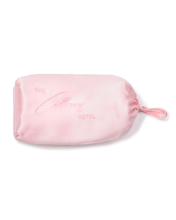 A pastel pink satin drawstring bag with The Colony Hotel embroidery, closed on the right by a matching drawstring, complements Petite Plume’s luxurious pajamas perfectly.