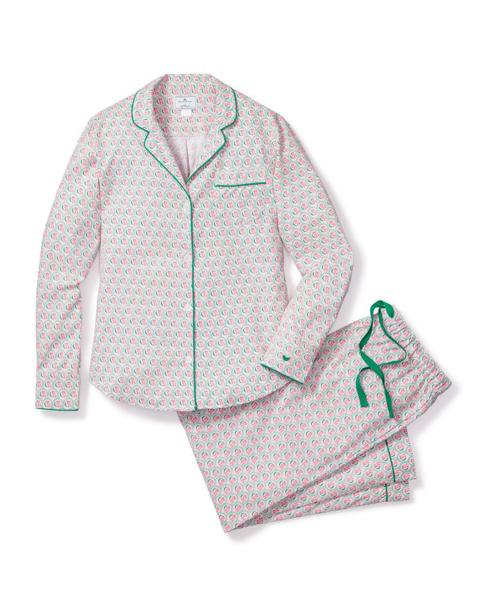 The Colony Hotel x Petite Plume Womens Exclusive Print Pajama Set features a pink and green floral pattern. The top has a collar, button-down design, and green piping, while the pants include a green drawstring. Both pieces are shown flat on a white background.