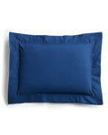 The Decorative Pillow in Navy by Petite Plume, with a darker bordered edge, crafted from luxurious percale fabric, rests elegantly on a plain white background.