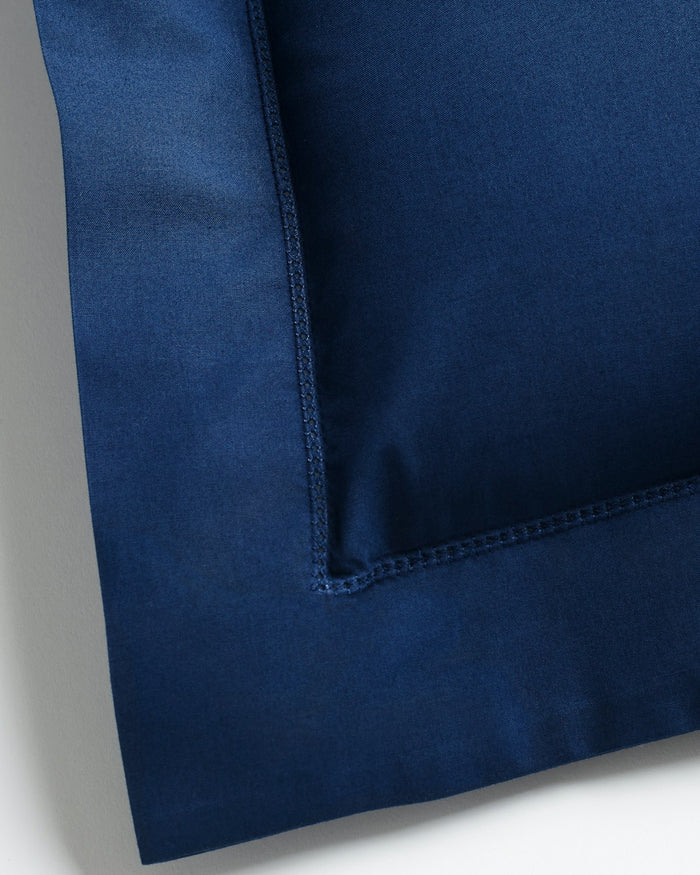 Close-up of a Decorative Pillow in Navy by Petite Plume, featuring visible stitching along the edges in percale fabric, displayed on a light surface.
