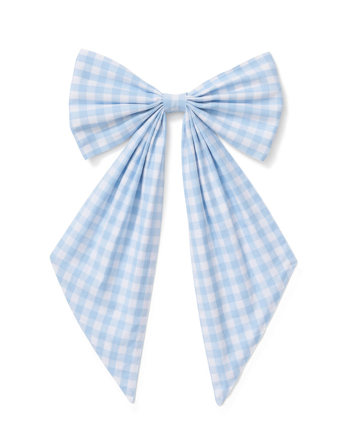A floral wreath of small white and pink blooms hangs on a beige door, adorned with the Easter Basket and Wreath Bow in Light Blue Gingham featuring long ribbon tails.