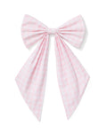 A spring wreath adorned with small white and pink flowers and greenery hangs on a beige door, finished with the Easter Basket and Wreath Bow in Pink Gingham at the bottom.