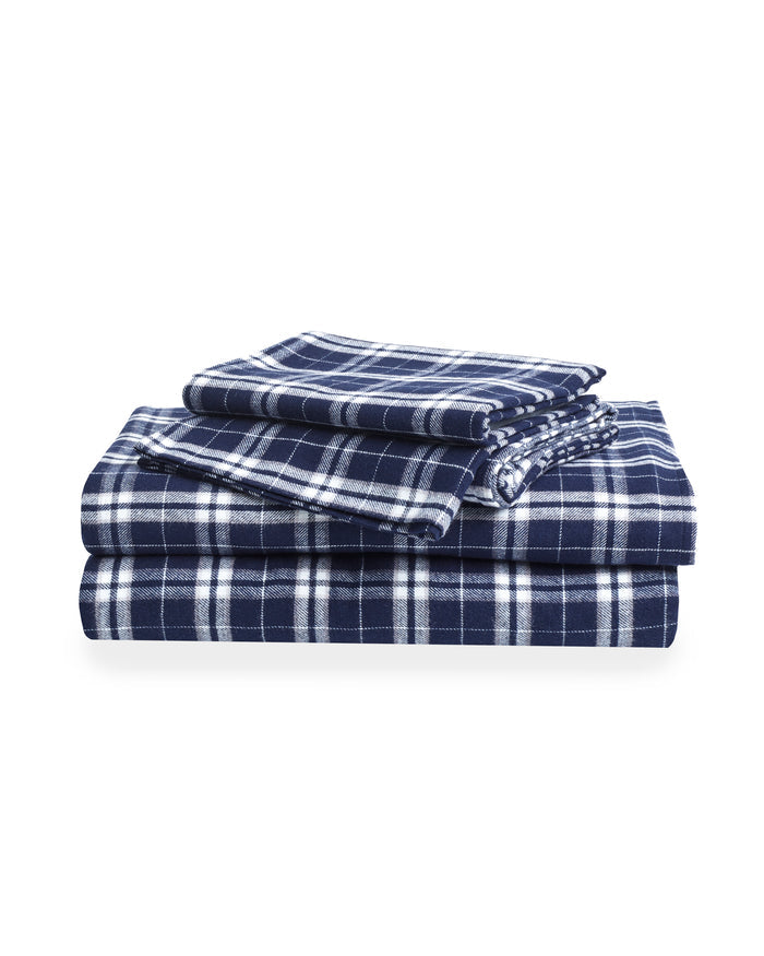 The Flannel Bed Sheet Set in Oxford Tartan features neatly folded navy blue and white plaid sheets with matching pillowcases, displayed on a white background.