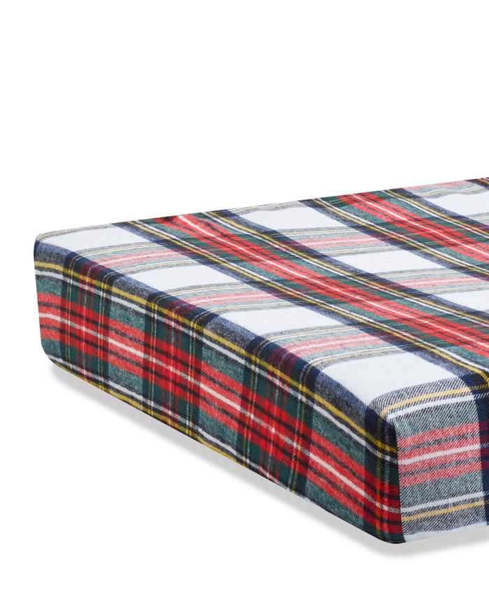 Close-up of Petite Plumes Flannel Crib Sheet in Balmoral Tartan showcasing a vibrant plaid design with red, white, blue, green, and yellow stripes. The circular gathered pattern creates a ruffled texture similar to a cozy cotton flannel sheet set.