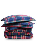 The Petite Plume Flannel Duvet Set in Windsor Tartan, featuring a blue, red, and yellow plaid pattern, is neatly folded. Made of brushed cotton flannel, the duvet and stacked pillows showcase a classic tartan design for cozy nights.