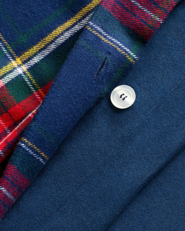 The Petite Plume Flannel Duvet Set in Windsor Tartan, featuring a blue, red, and yellow plaid pattern, is neatly folded. Made of brushed cotton flannel, the duvet and stacked pillows showcase a classic tartan design for cozy nights.