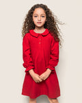 A young girl with long, curly hair stands against a plain background, wearing the Petite Plume Girls Flannel Victoria Nightgown in Red with a collar and buttons. Made from flame-retardant fabric resembling childrens sleepwear, her hands are clasped as she gazes directly at the camera.