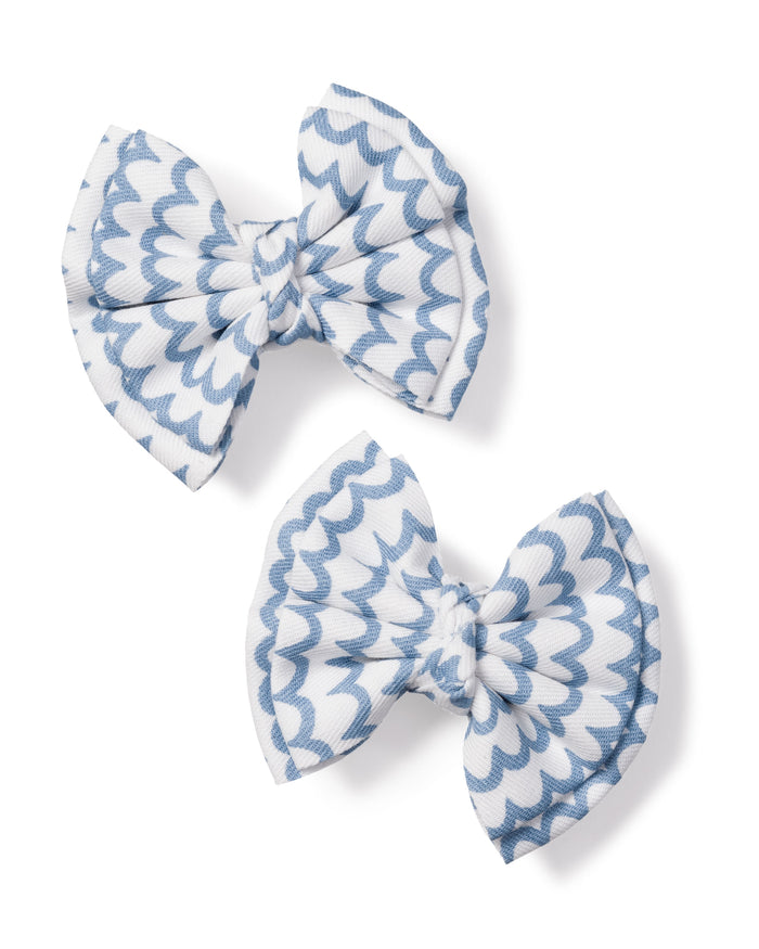 The Girls Hair Bows in La Mer by Petite Plume, featuring charming white and light blue scalloped patterns, make the perfect accessory for girls. Positioned diagonally on a plain white background, these elegant bows add a touch of sophistication to any outfit.