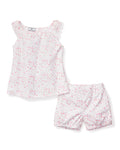 The Girls Twill Amelie Short Set in Dorset Floral by Petite Plume is a cotton pajama set with a sleeveless top and shorts, featuring white fabric adorned with delicate pink flower buds and ruffled shoulder accents for a feminine touch.