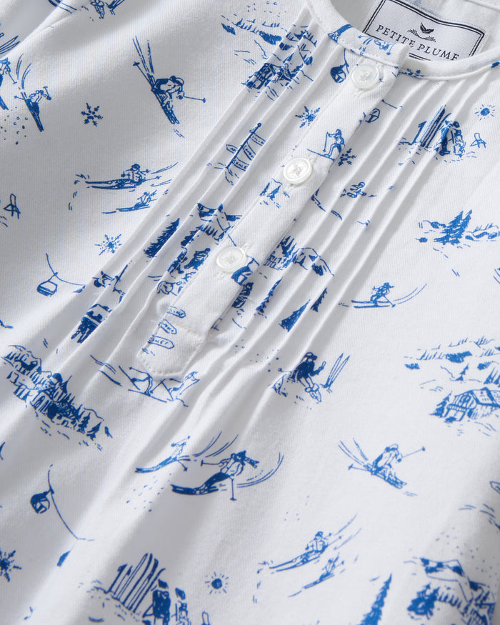 The Girl's Twill Beatrice Nightgown in Chalet Toile features long sleeves, knee-length, white fabric with blue scenic prints, a round neckline, pintucks on the chest, a loose fit, and button details at the neck.
