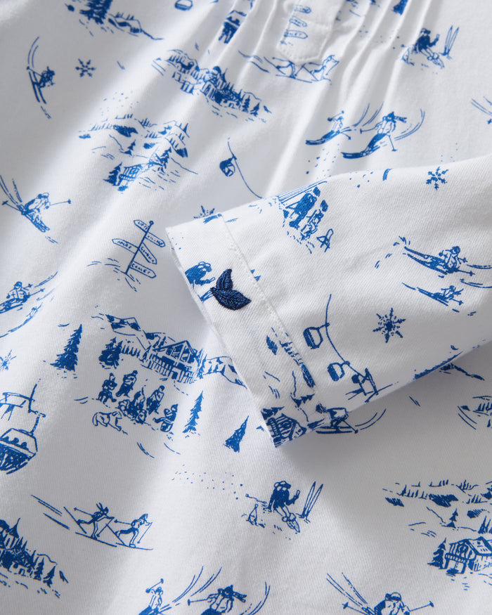 The Girl's Twill Beatrice Nightgown in Chalet Toile features long sleeves, knee-length, white fabric with blue scenic prints, a round neckline, pintucks on the chest, a loose fit, and button details at the neck.