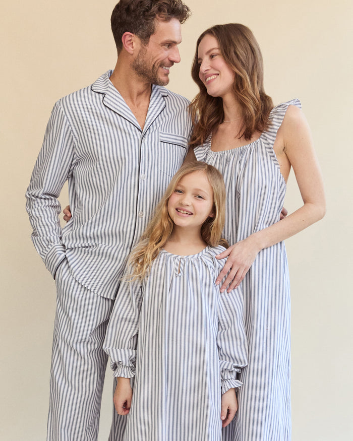 The Petite Plume Girls Twill Delphine Nightgown in Navy French Ticking has a loose fit with ruffled cuffs, vertical stripes, a gathered neckline with keyhole detail, and a relaxed silhouette. It is perfect for childrens sleepwear and crafted from flame-retardant fabric.